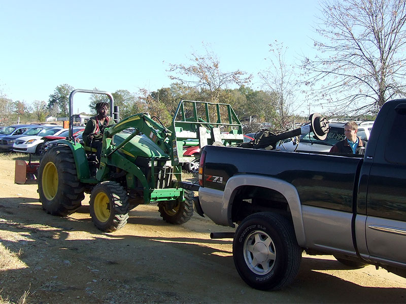 Dismantler Shawn uses heavy equipment to safely load an axle assembly into a customer's truck bed